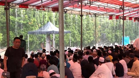Muslims perform Eid prayers while keeping dry under tentage built by Shen Fu Gong Temple despite heavy rain