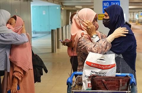PENUH EMOSI: Jemaah umrah yang dikuarantin di Abu Dhabi, Cik Avathali Azizah (paling kanan), berpelukan dengan Cik Hasnah Abdullah sambil menangis di Lapangan Terbang Changi semalam, mengenang pengalaman yang dilaluinya. Seorang lagi jemaah, Cik Zuha