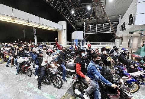 SORAK GEMBIRA: Ramai penunggang motosikal ghairah dan bersorak gembira setelah sempadan dibuka semula di pusat pemeriksaan Tuas pada 11.59 malam, 31 Mac 2022. - Foto BH oleh DESMOND FOO