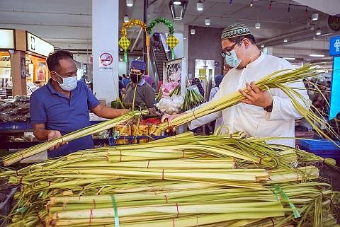 BELI JANUR: Seorang pelanggan dilihat sedang memilih janur yang dijual Encik Misra Lan (kiri) di Pasar Geylang Serai semalam. - Foto BH oleh NUR DIYANA TAHA