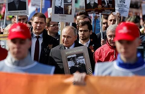 SAMBUT HARI KEMENANGAN: Encik Vladimir Putin (tengah) berjalan bersama sebilangan rakyat Russia dalam satu perarakan sempena Hari Kemenangan di Moscow. - Foto REUTERS