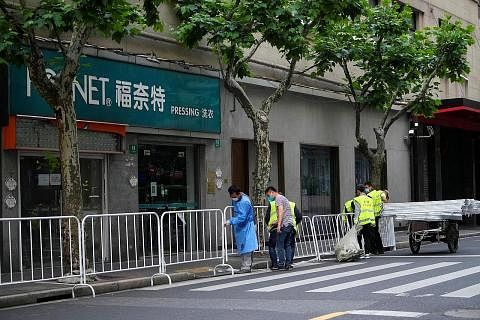 SEKATAN DILONGGAR: Pekerja memeriksa penyekat di Shanghai kelmarin. Penyekat itu dijangka ditiadakan secara bertahap apabila kes Covid-19 terus berkurangan. - Foto REUTERS