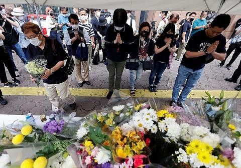PEMERGIAN MENGEJUT: Orang ramai semalam beratur untuk meletakkan jambangan bunga dan berdoa di tapak mantan Perdana Menteri Shinzo Abe (gambar sisipan) ditembak mati semasa berkempen berdekatan stesen Yamato-Saidaiji di Nara, Jepun. - Foto REUTERS