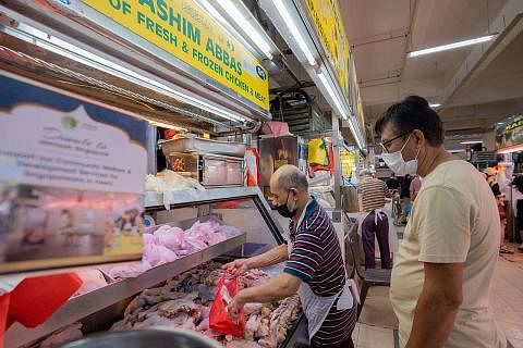 BUAT PENYESUAIAN: Pemilik Hashim Abbas Supplier of Fresh & Frozen Chicken & Meat, Encik Hashim Abbas (kiri) kelihatan mengendali pelanggan di gerainya di Pasar Geylang Serai semalam. - Foto-foto BH oleh NUR DIYANA TAHA