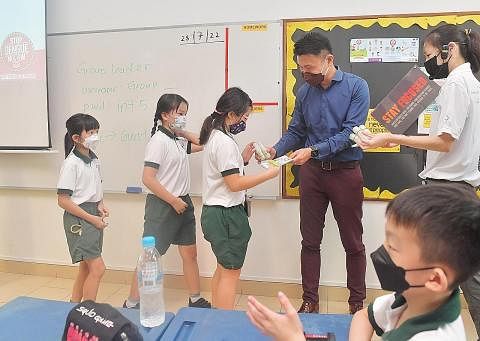 CEGAH DENGGI: Setiausaha Parlimen Kanan (Kemampanan dan Alam Sekitar), Encik Baey Yam Keng (baju biru), mengagih bahan penghalau nyamuk di Sekolah Rendah Pei Tong