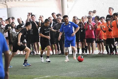 TUNJUK KEBOLEHAN: Encik Edwin Tong (tengah) dan Fandi Ahmad (kanan) beraksi untuk mengumpul $111,000 dalam acara Futsal Amal Singapore Exchange Bull Charge. - Foto SGX