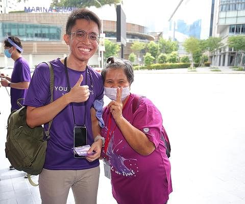 BERI SOKONGAN: Sukarelawan Pasukan Belia Singapura (YCS), Encik Syazwan Zainal Shah (kiri), berinteraksi dengan klien rakan kongsi komuniti YCS, Thye Hua Kwan Moral Charities, di The Purple Parade, Sabtu lalu.