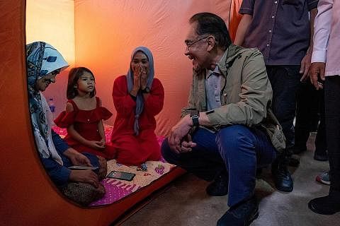 AMBIL PEDULI: Datuk Anwar beramah-tamah dengan mangsa banjir di pusat perlindungan di Pasir Mas, Kelantan, bulan lalu. - Foto REUTERS PERKUKUH HUBUNGAN: Datuk Anwar (kiri) menyambut Menteri Luar Singapura, Dr Vivian Balakrishnan, yang mengunjungi bel