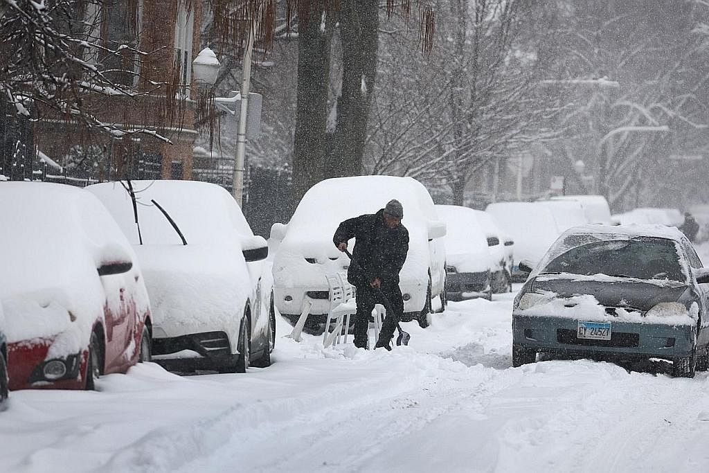RIBUT DI AMERIKA: Seorang penduduk menyodok salju di tempat meletak kereta di Chicago, Illinois. Satu ribut musim sejuk dijangka melanda kawasan Midwest Amerika, dan diramalkan menurunkan salji setebal satu hingga dua kaki di beberapa tempat. - Foto 