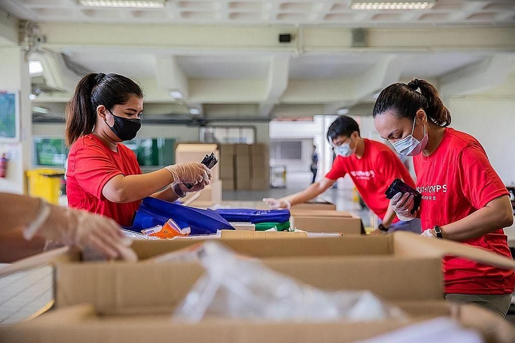 BELIA BERTINDAK: Sukarelawan daripada Pasukan Belia Singapura menyingsing lengan bagi menyiapkan bungkusan habuan untuk diagihkan kepada pekerja migran, sempena sambutan Hari Kebangsaan 2021 dan Hari Migran Antarabangsa 2021. - Foto-foto MAJLIS BELIA