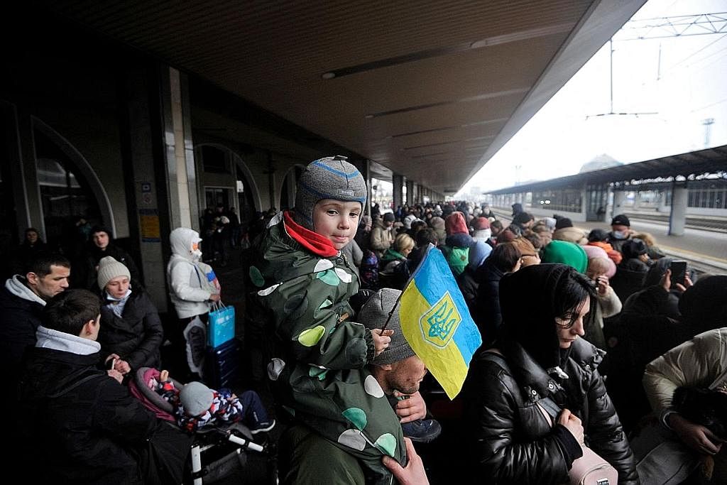TUNGGU KERETA API: Seorang budak lelaki yang memegang bendera Ukraine berada di bahu seorang lelaki ketika mereka di stesen kereta api Kyiv kelmarin. - Foto AFP