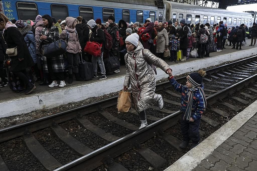 JADI PELARIAN: Seorang wanita bersama anaknya berjalan di landasan kereta api di bandar Lviv, barat Ukraine, sedang penduduk Ukraine melarikan diri ke kawasan barat negara itu atau negara-negara jiran Eropah lain. - Foto EPA-EFE