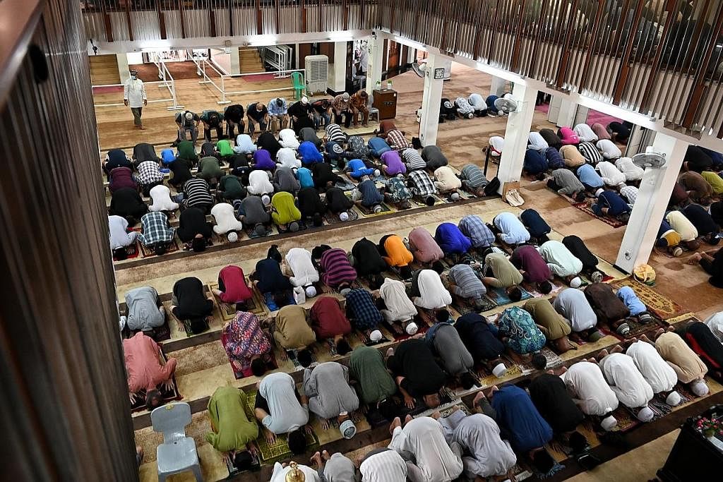 'LEBIH MERIAH': Jemaah Masjid Kampung Siglap menunaikan solat Jumaat semalam dengan saf rapat. Relawan 'orang kuat' masjid itu, Encik Othman Kasim (baju hitam) yang membantu jemaah, berkata keadaan "lebih meriah", tetapi ada jemaah masih tidak pasti 