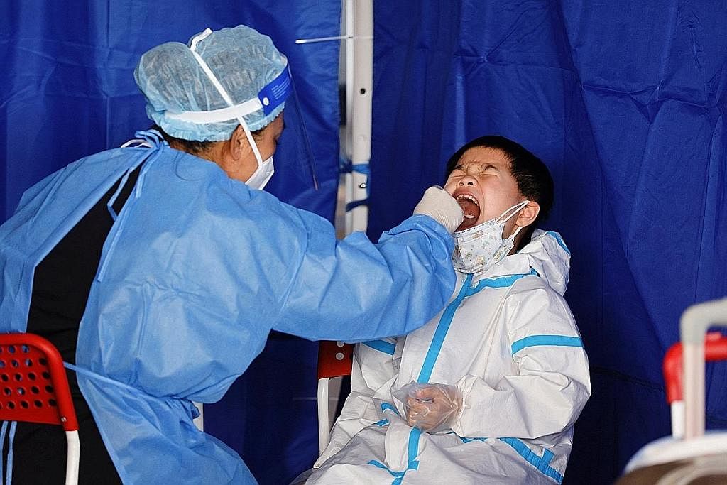PENJAGAAN KESIHATAN: Seorang kanak-kanak yang memakai alat pelindung diri (PPE) menjalani calitan di rongga mulut bagi ujian asid nukleid di Jambatan Hong Kong-Zhuhai-Macao di Pelabuhan Hong Kong, kelmarin, di tengah-tengah pandemik Covid-19 di wilay