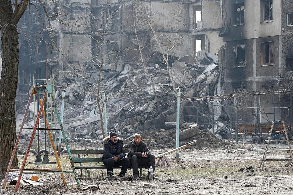 MUSNAH: Dua penduduk di Mariupol duduk di bangku berhampiran blok perumahan yang musnah dibedil tentera Russia. Ratusan ribu penduduk di kota pelabuhan itu dianggarkan masih terperangkap di sana. - Foto REUTERS