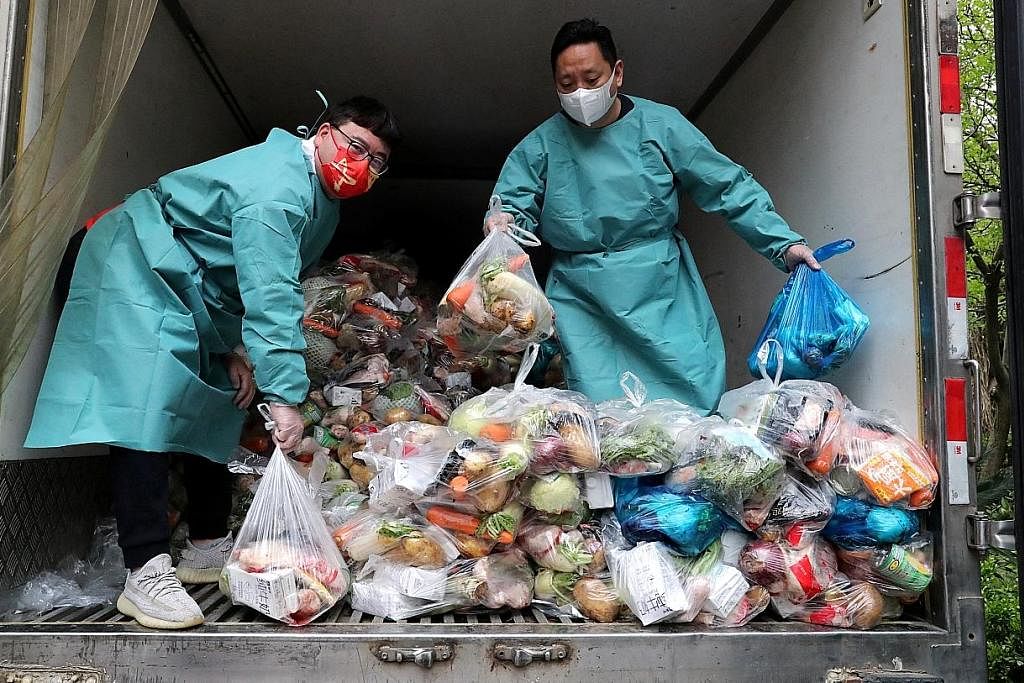 ATUR MAKANAN: Dua pekerja sedang mengatur beg berisi sayur dan keperluan lain di dalam sebuah trak untuk diagihkan kepada penduduk di sebuah apartmen di Shanghai sedang bandar itu melaksanakan sekatan penuh demi membendung penularan Covid-19. - Foto 