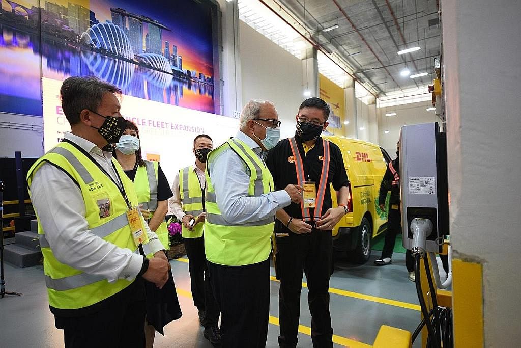 SASAR HAPUS PELEPASAN CO2: Encik Iswaran (tengah) mempelajari tentang tempat mengecas EV yang akan dipasang di pusat khidmat DHL Express Singapore.