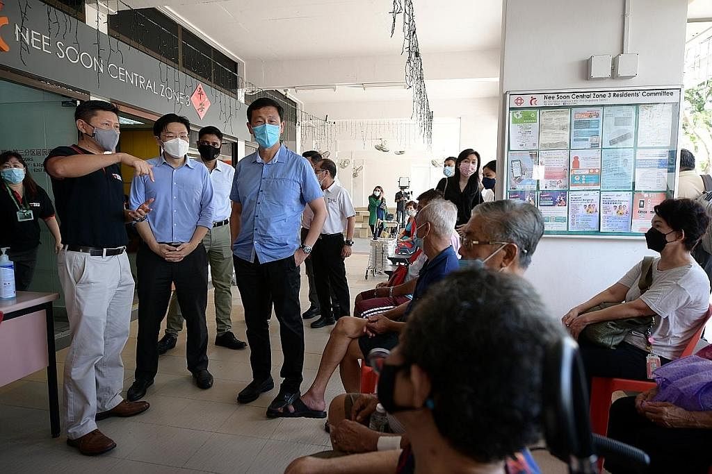 GALAK DAPATKAN VAKSIN: Encik Lawrence Wong (dua dari kiri) dan Encik Ong Ye Kung (kanan) mengunjungi pusat vaksinasi mudah alih di Nee Soon Central semalam. - Foto BH oleh NG SOR LUAN