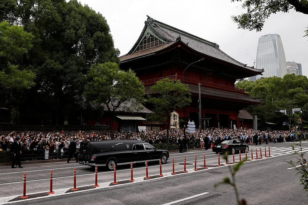 LAMBAIAN TERAKHIR: Orang ramai di tepi jalan memberi lambaian terakhir kepada mendiang Shinzo Abe yang dibawa van mayat melalui beberapa kawasan di pusat bandar Tokyo. - Foto REUTERS