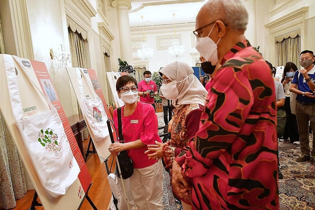 HASIL KARYA SENI: Puan Halimah (dua dari kanan) melihat karya seni pelukis, Cik Katy Lee (kiri), dari Persatuan Orang Cacat Penglihatan Singapura (SAVH) di rumah terbuka sempena sambutan Hari Kebangsaan di Istana semalam. - Foto BH oleh DESMOND WEE