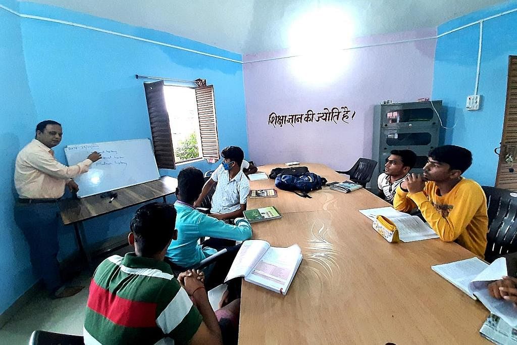 SEDIAKAN DIRI UNTUK PEKERJAAN: Seorang pegawai pemerintah (kiri) membantu pelajar mempersiap diri bagi peperiksaan yang harus dilalui untuk mendapatkan pekerjaan dengan pemerintah, di sebuah perpustakaan masyarakat di Kampung Charghara di Jamtara, In