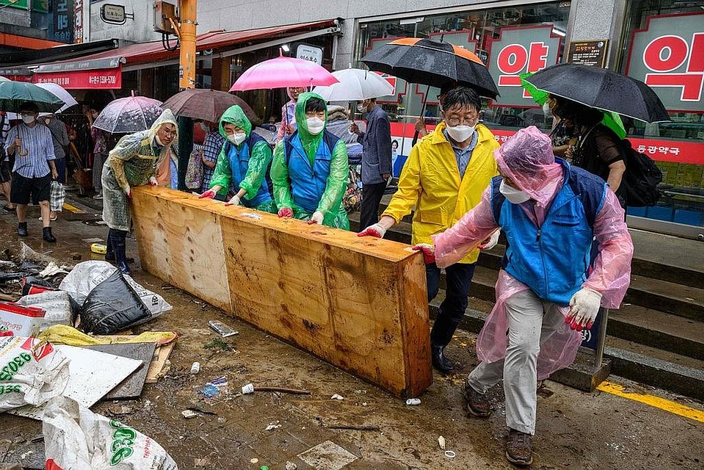 KERJA PEMBERSIHAN: Sekumpulan pekerja membersihkan longgokan sampah sarap di kawasan Pasar Namseong di daerah Gangnam kelmarin selepas hujan lebat terburuk melanda tempat itu.