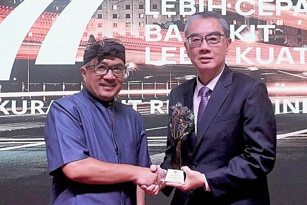 SAMPAIKAN ANUGERAH: Duta Besar Indonesia ke Singapura, Encik Suryo Pratomo (kiri) menyampaikan Anugerah Adinata kepada Pengerusi SIF, Encik Ong Keng Yong. - Foto SIF