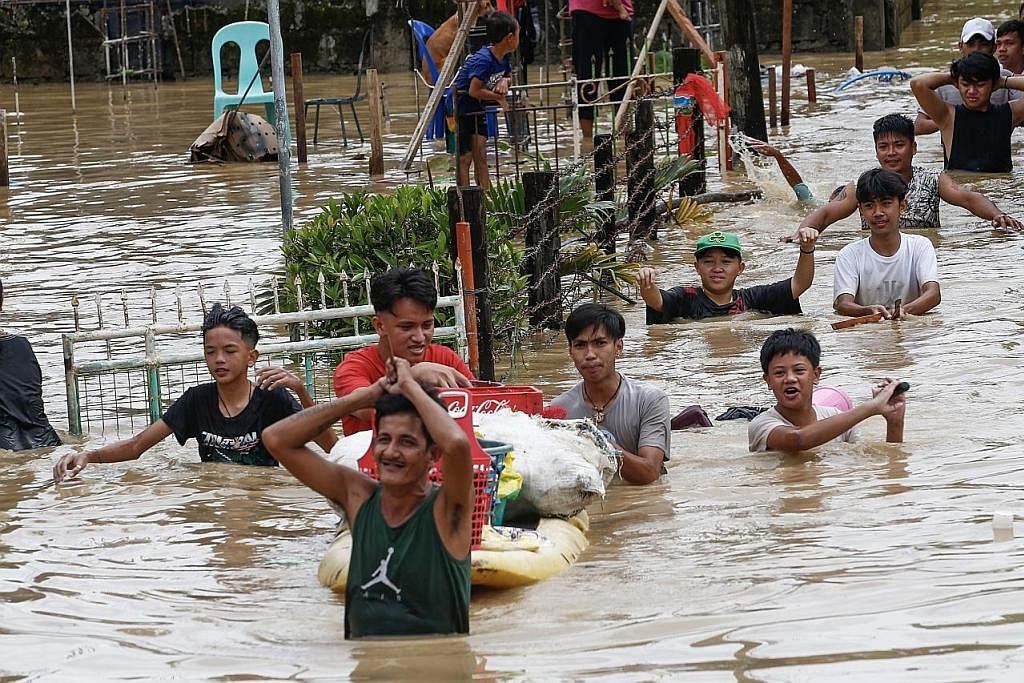 ANGKARA 'NORU': Penduduk mengharungi banjir akibat taufan Noru di bandar San Miguel di wilayah Bulacan, utara Manila semalam. - Foto EPA-EFE
