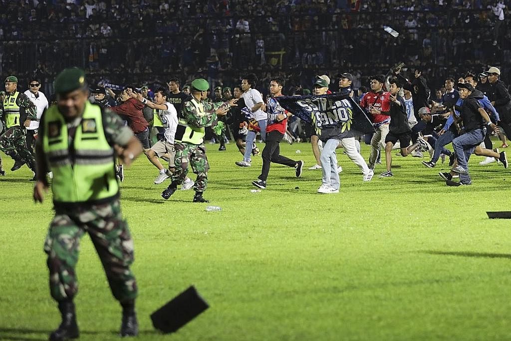 REMPUH PADANG: Penonton dan penyokong kelab bola sepak Arema FC dan Persebaya Surabaya masuk ke dalam padang dan bertempur sesama mereka sedang pasukan keselamatan gagal mengawal keadaan hingga mengakibatkan lebih 130 maut dan hampir 200 yang lain ce