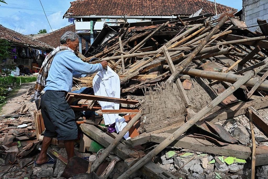 CARI BARANGAN: Penduduk kampung di Jawa Barat yang dilanda gempa bumi, Encik Rosyid Rusli, mencari apa jua barangan yang boleh diselamatkannya di bawah timbunan rumahnya di Cugenang, Cianjur, termasuk pakaian ganti. - Foto AFP MASIH BERHARAP: (Gambar