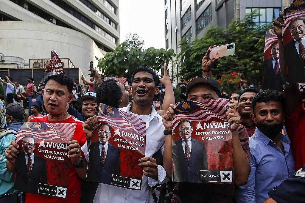 DAPAT SOKONGAN: Penyokong Datuk Seri Anwar Ibrahim menunjukkan sokongan mereka kepada pemimpin itu dengan slogan Anwar Untuk Rakyat Malaysia. - Foto EPA-EFE PERDANA MENTERI BARU: Datuk Seri Anwar (kiri) sempat bergambar bersama (dua dari kiri) Yang d